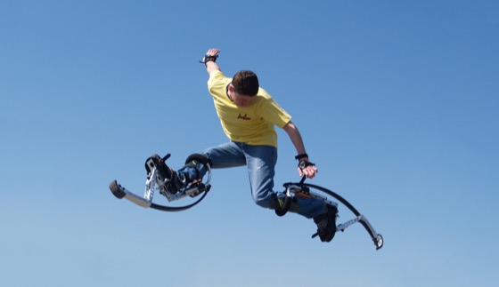 Une personne en plein vol sur des échasses à ressort Skyrunner sous un ciel bleu dégagé